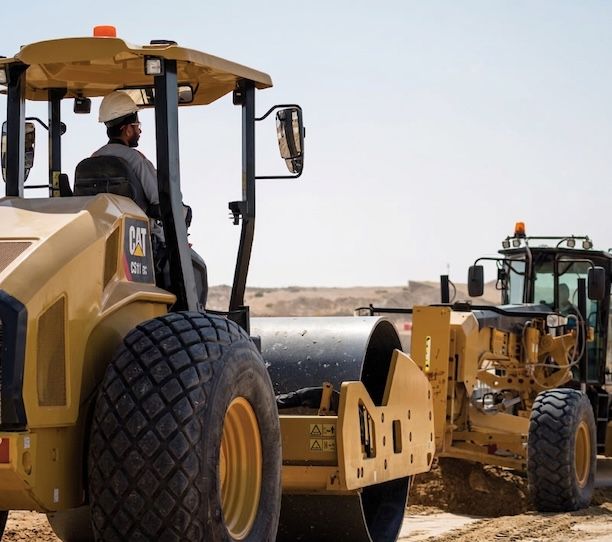 Caterpillar roller and grader being operated on a job site