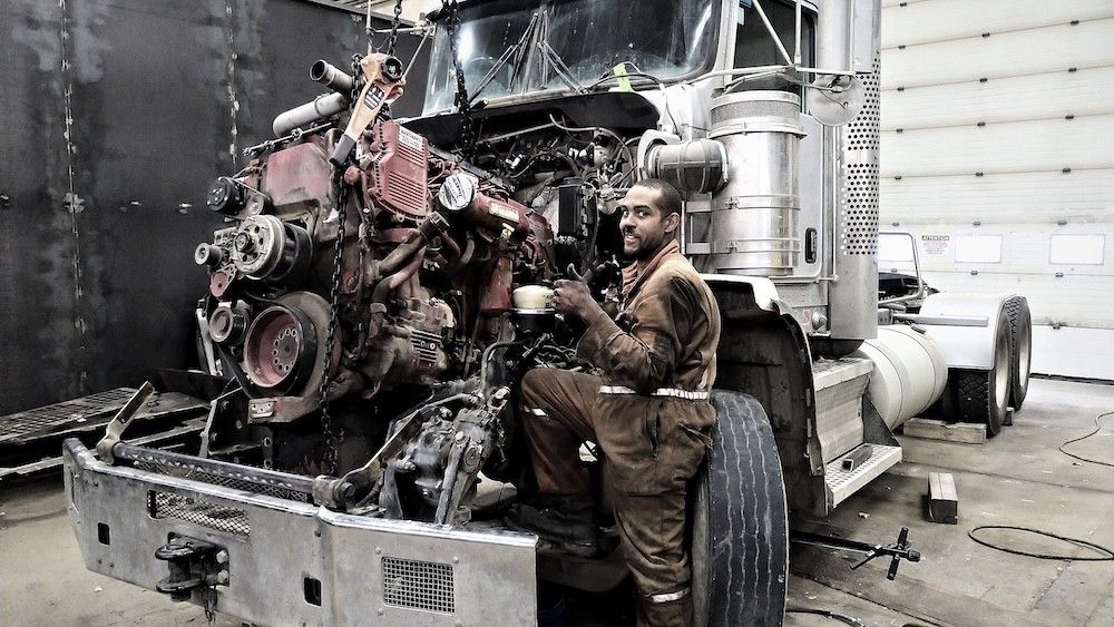 Mach 6 technician working underneath a highway truck during a driveline repair
