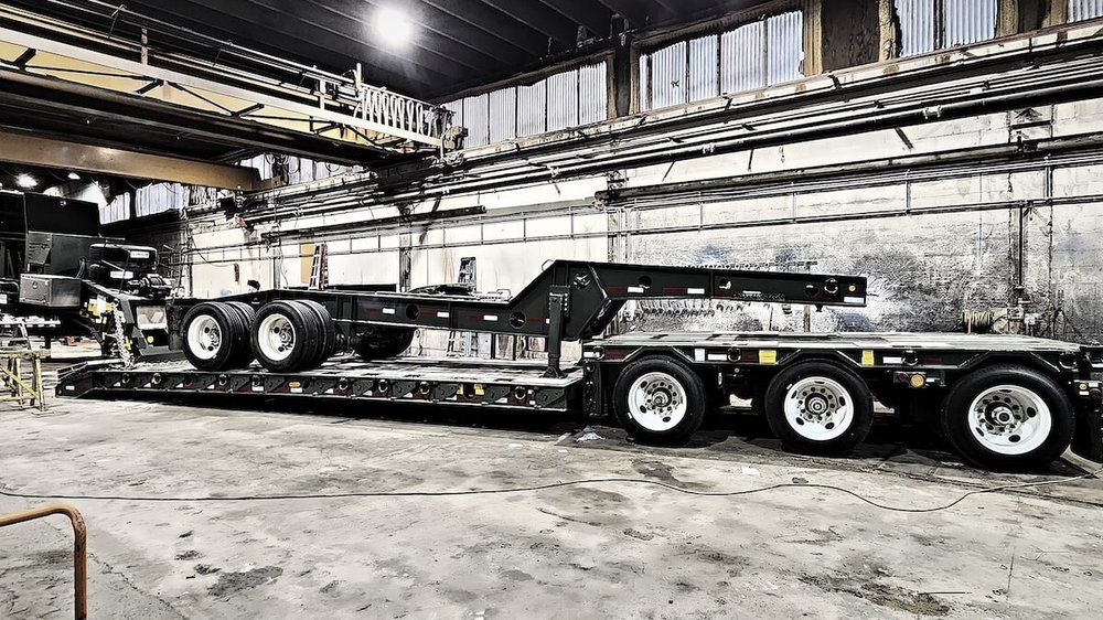 Tridem lowboy trailer in the Mach 6 shop bay under the overhead crane