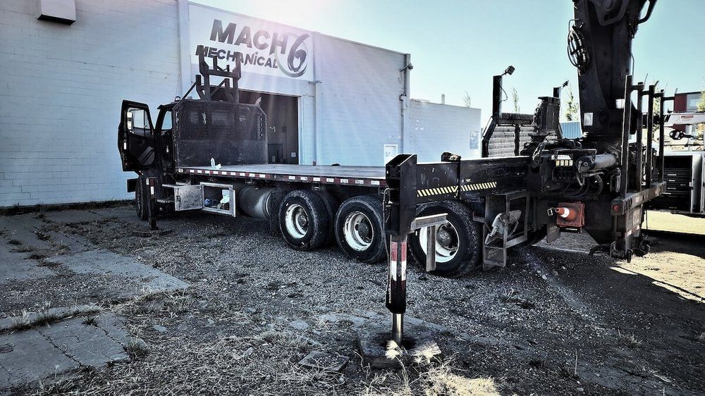 Picker truck on the pad outside the Mach 6 Mechanical building, company sign visible