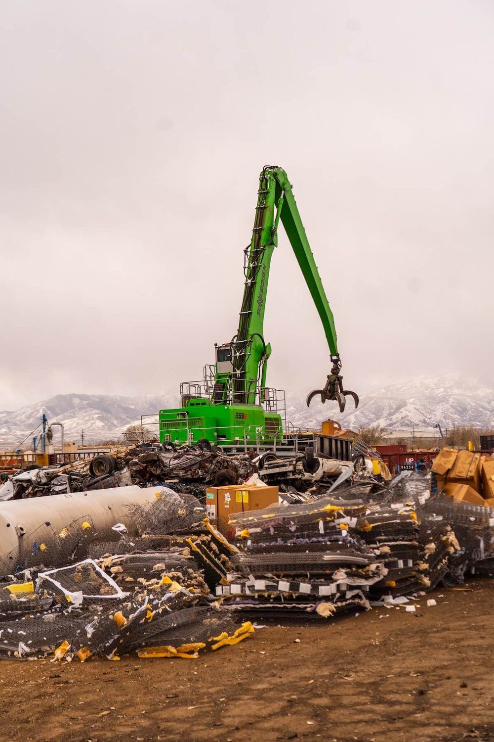 Manufacturer photo of a Sennebogen 855e material handler with grapple attachment in a scrap yard