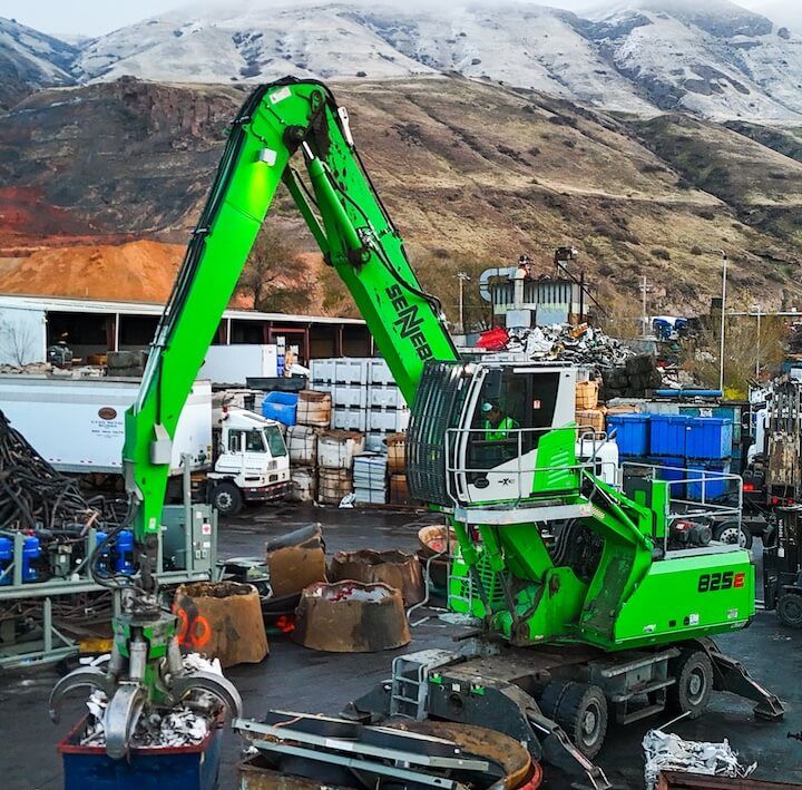 Manufacturer photo of a Sennebogen material handler demonstrating hydraulic reach in a scrap yard