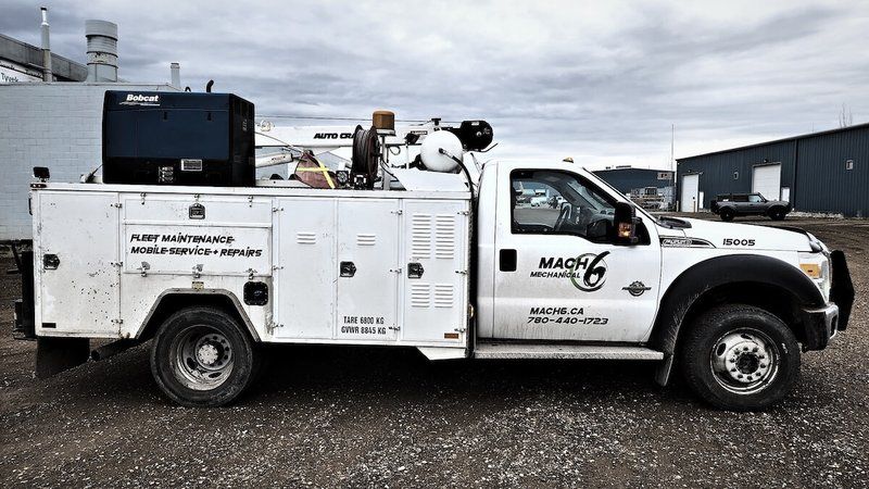 Mach 6-decaled F-550 service truck with crane and compressor in the yard
