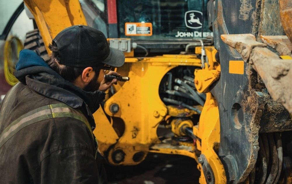 Mach 6 technician inspecting hydraulic linkage on a tracked machine